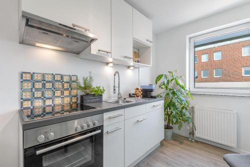 a kitchen with a sink and a stove at Mango Living I Apartment Hideaway I modern I 2 Schlafzimmer I 77qm in Mönchengladbach