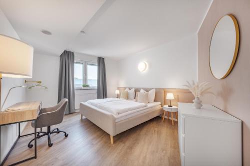 a white bedroom with a bed and a desk and a mirror at Mango Living I Apartment Hideaway I modern I 2 Schlafzimmer I 77qm in Mönchengladbach