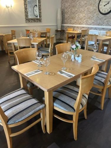 a wooden table and chairs with wine glasses on it at Drummond Hotel in Ballykelly