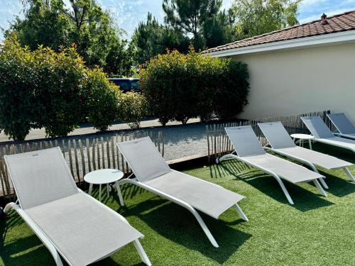 a row of lawn chairs and tables on the grass at La villa des Épicuriens - Arès - Bassin d'Arcachon in Arès