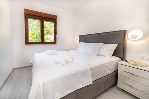 a bedroom with a large bed with white sheets and a window at Red Hill in Kotor