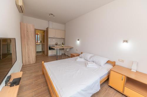 a bedroom with a large white bed and a kitchen at Red Hill in Kotor
