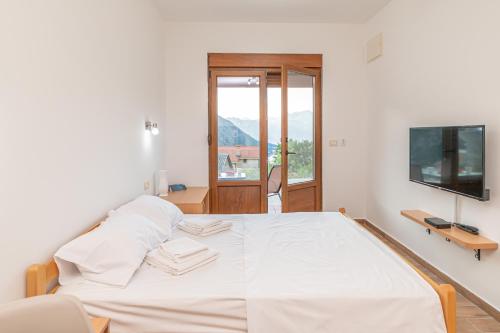 a bedroom with a bed with white sheets and a television at Red Hill in Kotor