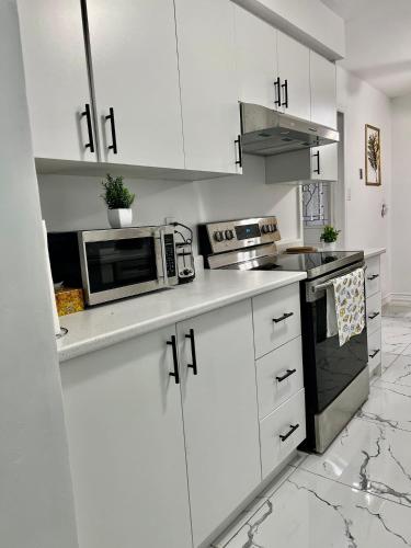 a white kitchen with white cabinets and a microwave at K9 Room Near Airport in Mississauga