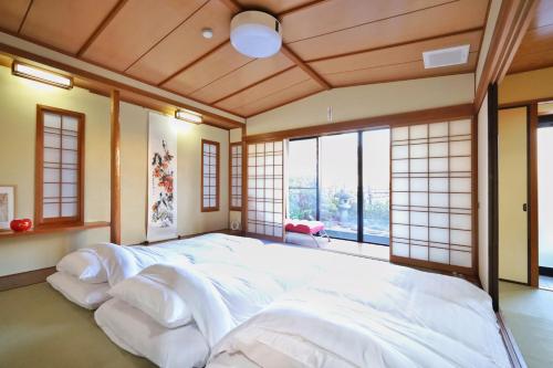 a large white bed in a room with windows at 錦糸町徒歩4分210平米大空間和風庭園テラススカイツリービュー畳部屋 in Tokyo