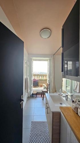 une cuisine avec un évier et une fenêtre dans l'établissement Le toit chic à 15 mn Paris Centre, à Romainville