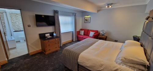 a bedroom with a bed and a tv and a chair at The Royal Hotel in Liverpool