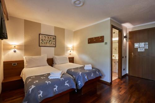 a hotel room with two beds and a hallway at Hotel Walser Courmayeur in Courmayeur