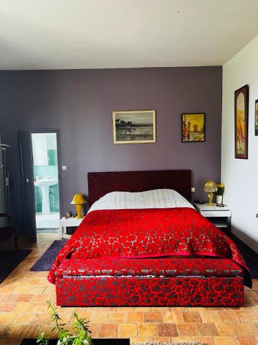 une chambre avec un grand lit avec une couverture rouge dans l'établissement Château de la Thibaudière - Chambre de la Reine, à Allonnes