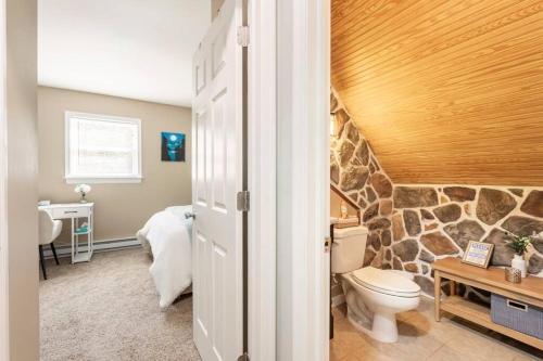 a bathroom with a toilet and a stone wall at The Beautiful & Cozy Malvec Chalet in Tobyhanna
