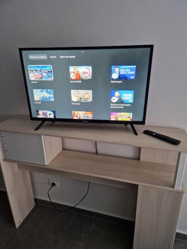 Elle comprend une télévision à écran plat installée au-dessus d'un support en bois. dans l'établissement Appart cosy proche gare RER E entre Paris-Disney, à Pontault-Combault