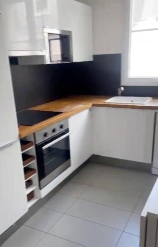 une cuisine avec des armoires blanches et un four à plaques de cuisson dans l'établissement Flexliving - room - Voltaire, à Paris