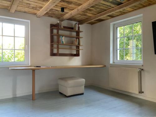 a room with a desk and a bench and two windows at Maison avec piscine privée au calme in Schlierbach