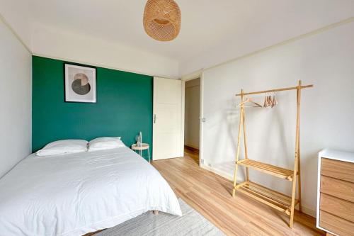 une chambre avec un lit blanc et un mur vert dans l'établissement Flexliving - room - Entrepreneur, à Paris