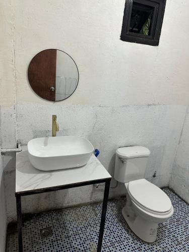 a bathroom with a sink and a toilet and a mirror at HaCaSeMa Transient House in Acala