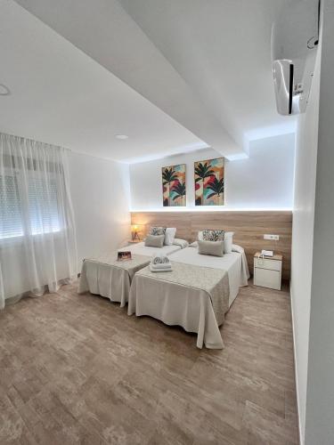 two beds in a room with white walls at Hotel Romerito in Málaga
