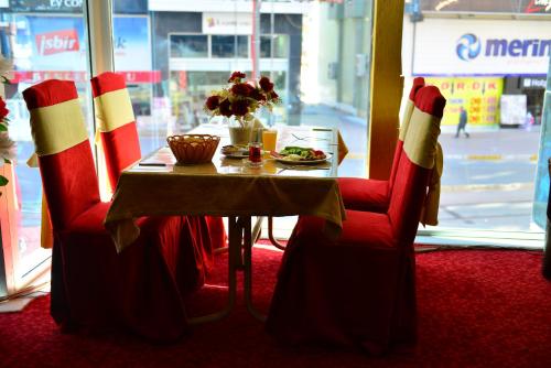 a table with red and white chairs and a table with a plate of food at Kivrak Hotel in Antalya
