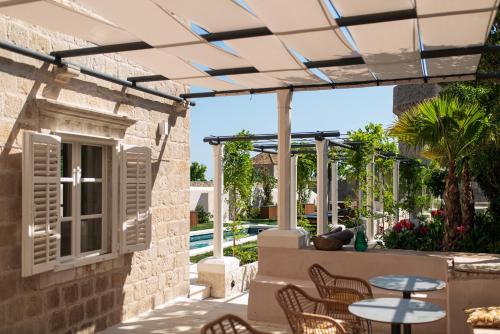 een terras met een tafel en stoelen onder een pergola bij HERITAGE VILLA SPINDLER by DuHomes in Dubrovnik