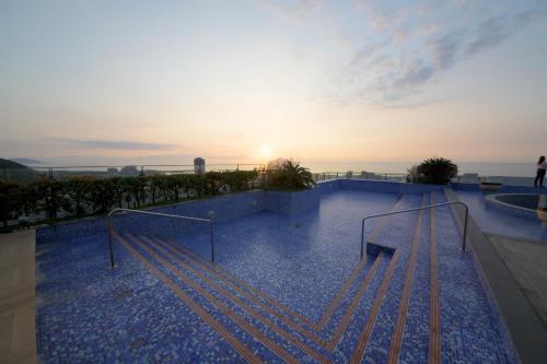 a swimming pool with a sunset in the background at 宜蘭頭城A Happy Birthday 私人溫泉 海景 蘭陽夜景大陽台無邊際泳池 in Toucheng