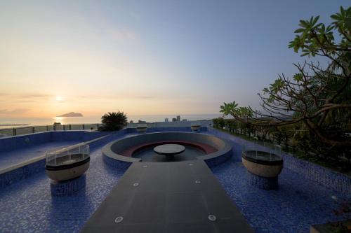 a building with a fountain on the roof with the sunset at 宜蘭頭城A Happy Birthday 私人溫泉 海景 蘭陽夜景大陽台無邊際泳池 in Toucheng