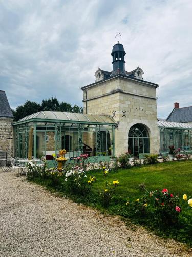a building with a greenhouse and flowers in the yard at Château de la Thibaudière Bois Savary - Chambre familiale du Roi in Allonnes