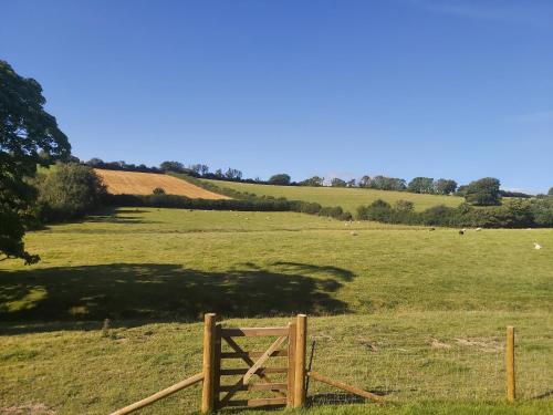 a wooden gate in a field with sheep in the distance at Cuckoo's Nest in Barnstaple