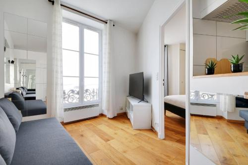 un salon avec un canapé et une télévision dans l'établissement GuestReady - Bel Apt. près du Mur des Je t'aime, à Paris