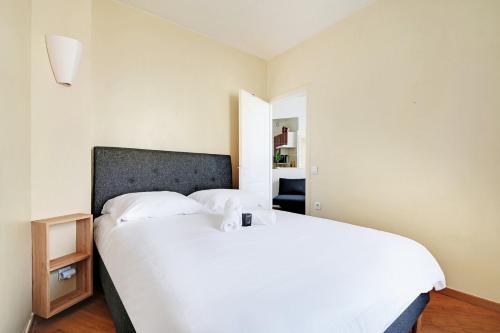 - une chambre avec un grand lit blanc et une table de nuit dans l'établissement GuestReady - Bel Apt. près du Mur des Je t'aime, à Paris