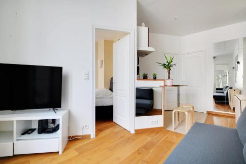 un salon avec une télévision à écran plat et une chambre avec un lit dans l'établissement GuestReady - Bel Apt. près du Mur des Je t'aime, à Paris