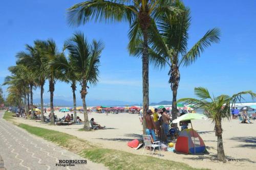 a group of people on a beach with palm trees at Casa espaçosa 6 min da praia in Bertioga