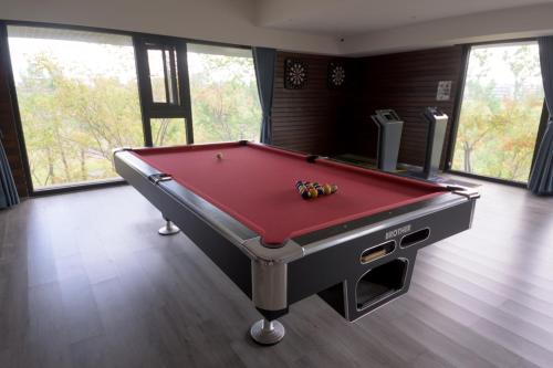 a red pool table in a room with windows at 宜蘭頭城A Happy Birthday 私人溫泉 海景 蘭陽夜景大陽台無邊際泳池 in Toucheng