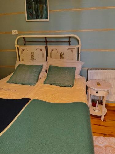 a bed with two green pillows on top of it at Dzveli Galavani -Old Wall in Tʼelavi
