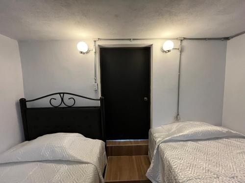 a bedroom with two beds and a black door at A pasos del mercado y centro histórico, diseño industrial in San José del Cabo
