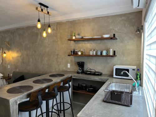 a kitchen with a counter and a counter top with stools at A pasos del mercado y centro histórico, diseño industrial in San José del Cabo