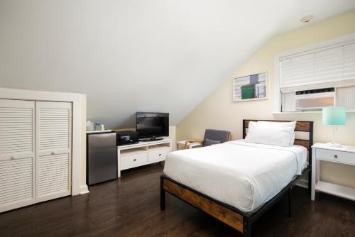 a bedroom with a bed and a flat screen tv at Southernmost Inn Adult Exclusive in Key West