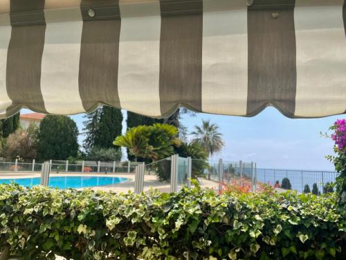 - une vue sur la piscine depuis un parasol dans l'établissement La Perle de Lilly, à Menton