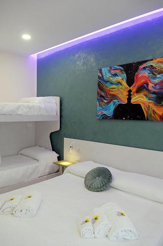 a bedroom with two beds and a painting on the wall at B&B AIDA Rooms Cefalù in Cefalù
