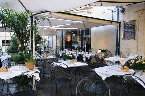 a restaurant with white tables and chairs and umbrellas at Hôtel du Palais des Papes in Avignon
