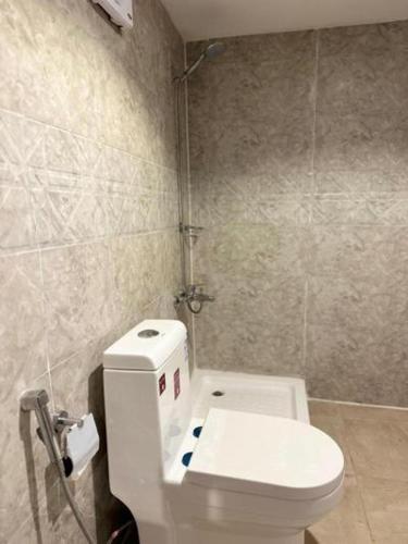 a bathroom with a white toilet and a sink at Studio overlooking pool amid flowering and quiet in Al-ʿUla
