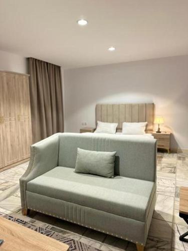 a couch in a living room with a bed at Studio overlooking pool amid flowering and quiet in Al-ʿUla