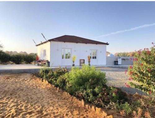 una piccola casa bianca su una spiaggia con cespugli di Studio overlooking pool amid flowering and quiet a Al Ula
