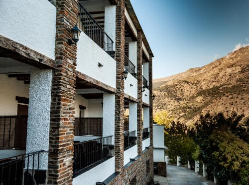 a brick building with a balcony and a mountain at Hotel La Fragua II in Trevélez