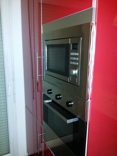 - un four micro-ondes dans une chambre avec un mur rouge dans l'établissement Résidence Le Parc 68, à Colmar