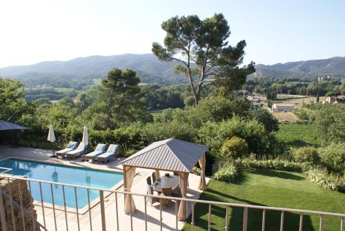 a villa with a swimming pool and mountains in the background at L'Irisciabella in Lourmarin