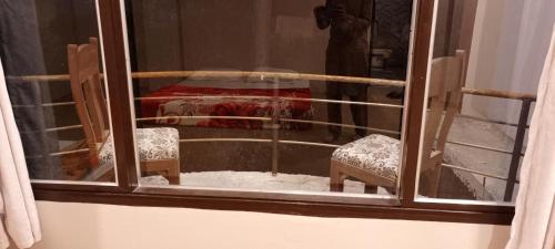 a window with two chairs and a table covered in snow at Ihram Hotel And Guest House in Swat