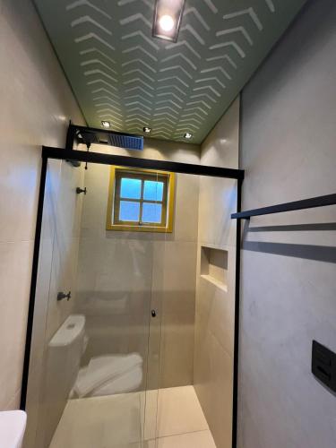 a bathroom with a shower and a toilet and a window at Pousada Refúgio de Maresias in Maresias