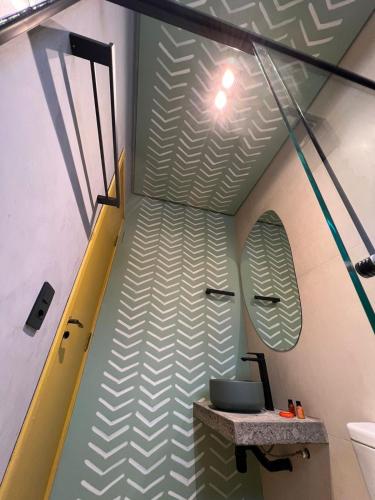 a bathroom with a green and white patterned wall at Pousada Refúgio de Maresias in Maresias