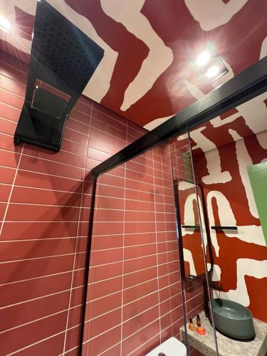 a bathroom with a mirror and a red tiled wall at Pousada Refúgio de Maresias in Maresias