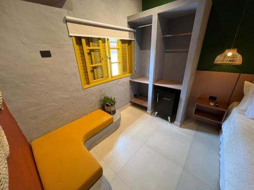 a bedroom with a yellow bench and a window at Pousada Refúgio de Maresias in Maresias