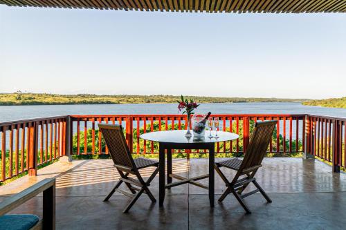 a table and chairs on a deck with a view of the water at Naara Eco Lodge & Spa in Chidenguele